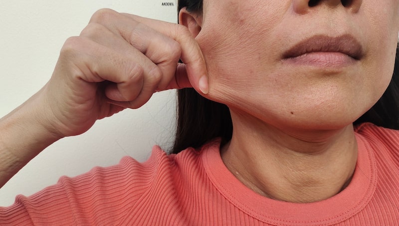Middle-aged woman stretching her cheek skin with her fingers